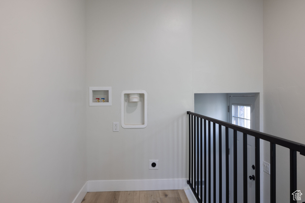 Laundry room with hookup for a washing machine, electric dryer hookup, light wood-style floors, and a high ceiling