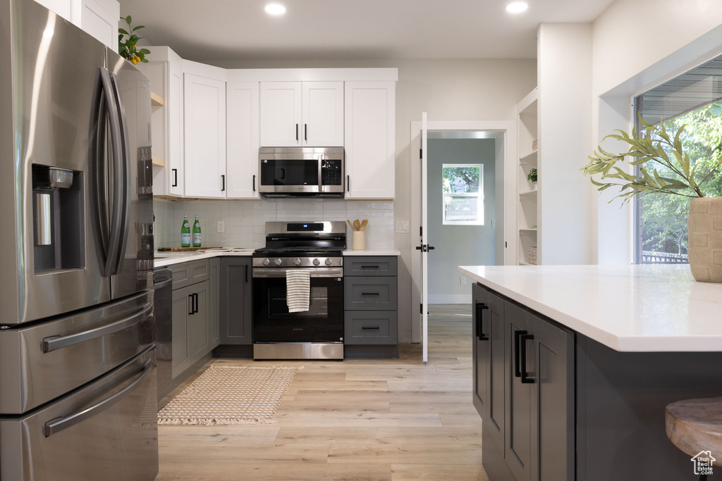 Kitchen featuring appliances with stainless steel finishes, gray cabinetry, light countertops, tasteful backsplash, and recessed lighting