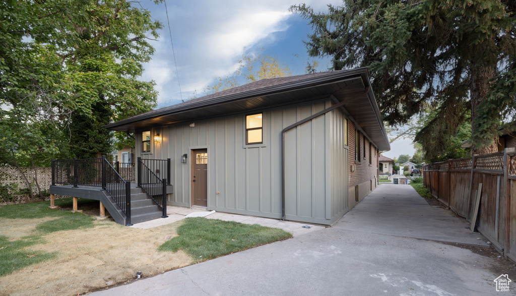 View of front of property with board and batten siding, a wooden deck, and driveway