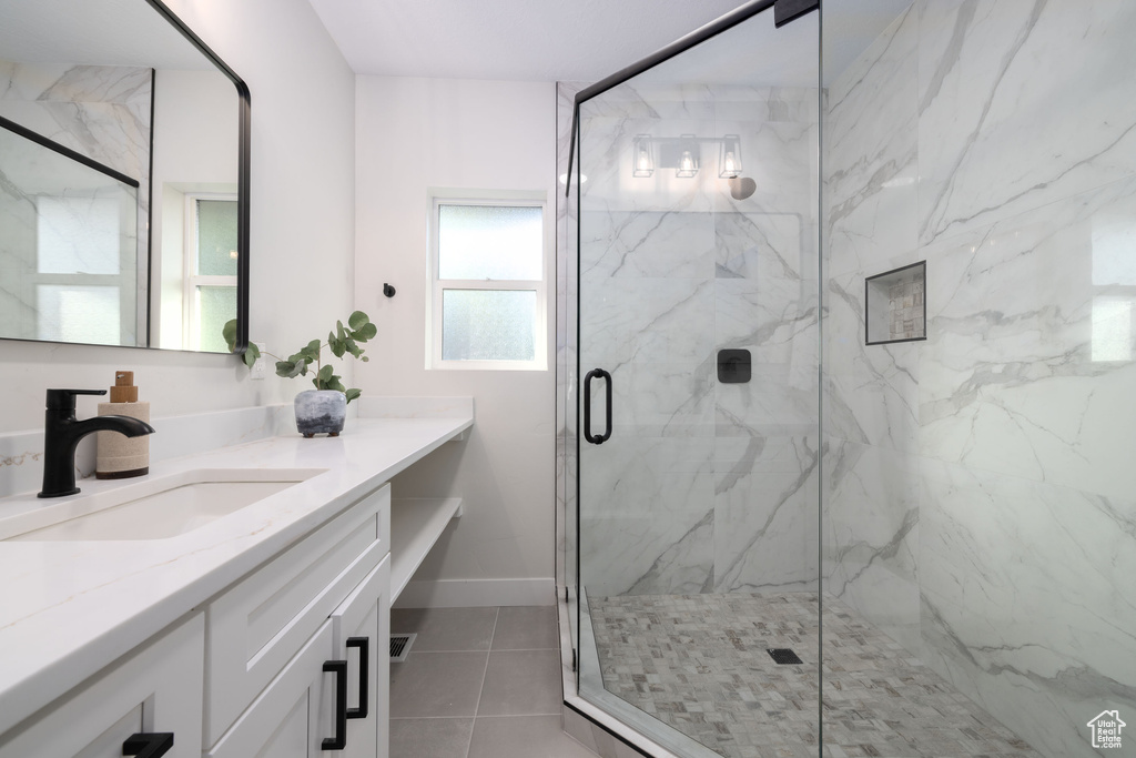 Full bath with vanity, a marble finish shower, and tile patterned flooring