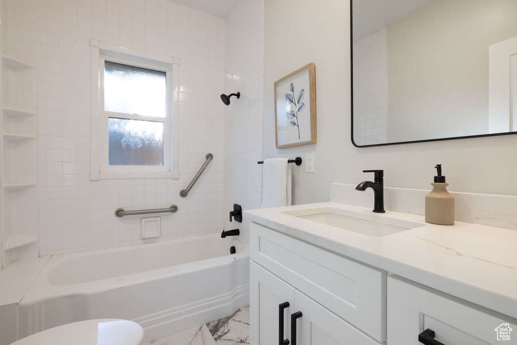 Bathroom featuring vanity, marble finish flooring, and shower / tub combination