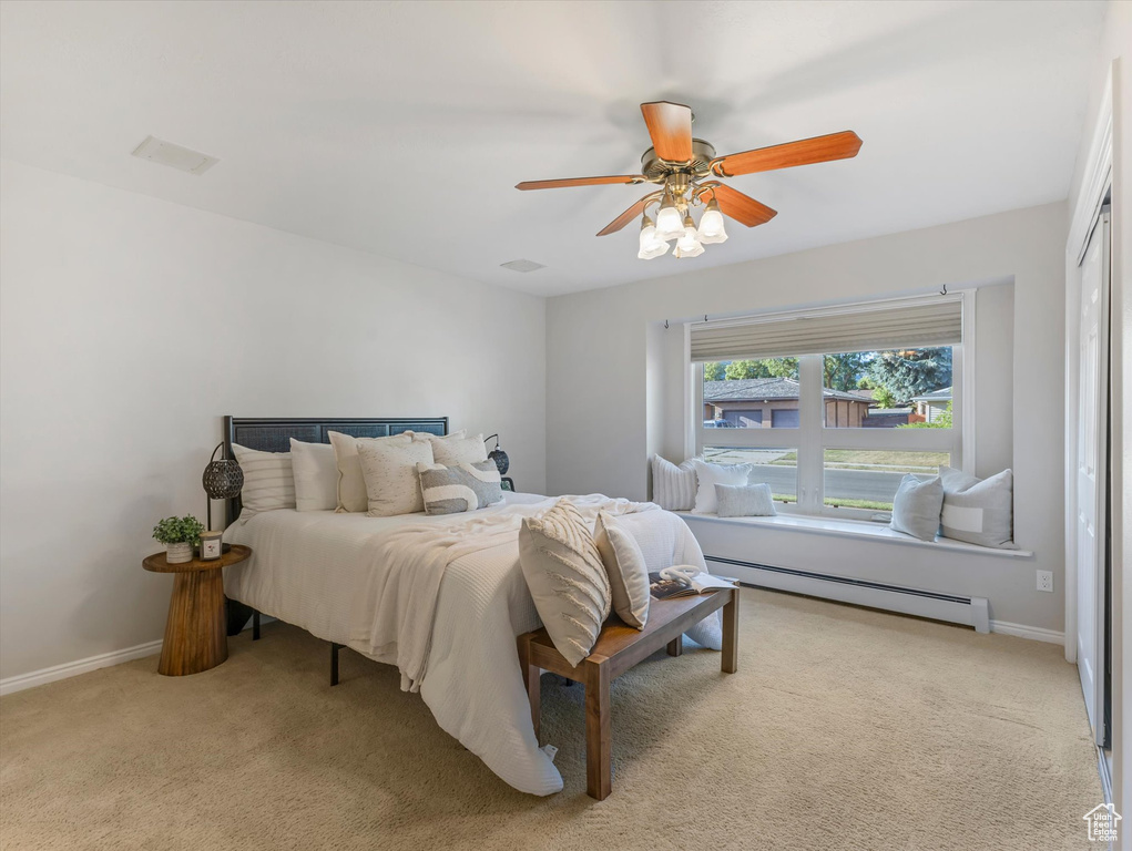 Bedroom featuring a baseboard heating unit, light carpet, and ceiling fan