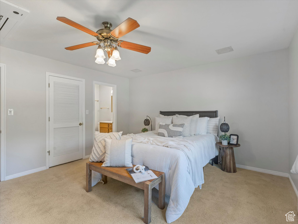 Bedroom with light colored carpet, a ceiling fan, and ensuite bath