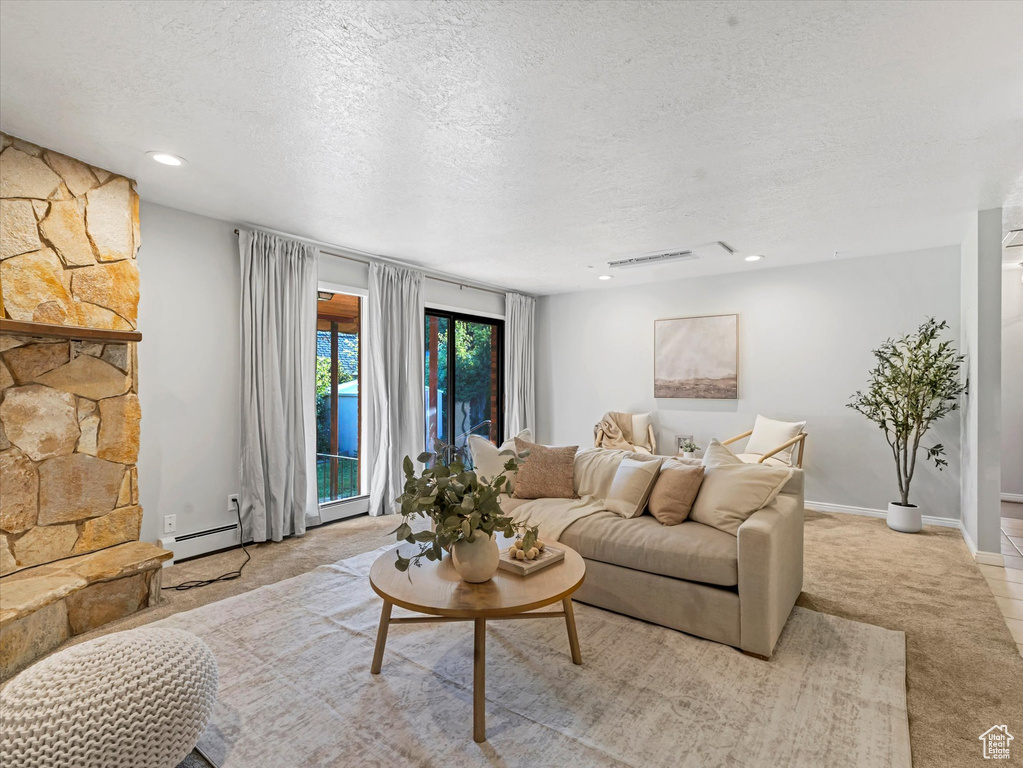 Living room with a baseboard radiator, a textured ceiling, recessed lighting, and carpet floors