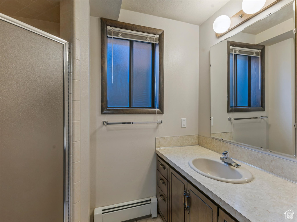 Bathroom with a baseboard radiator, a shower stall, and vanity