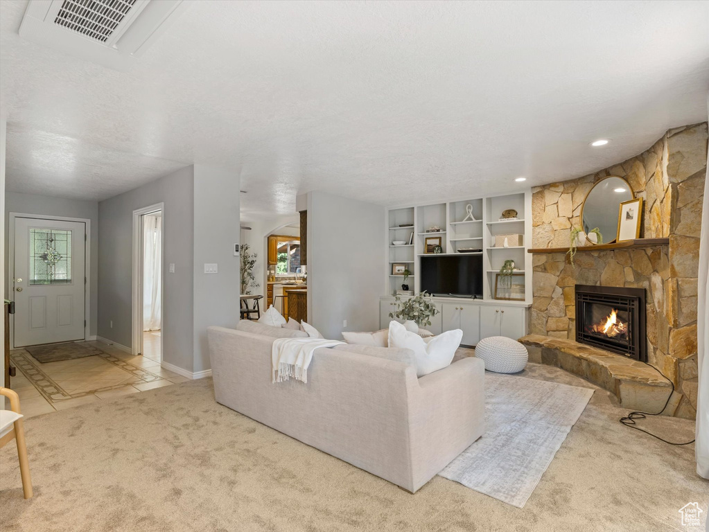 Carpeted living room with a stone fireplace and recessed lighting