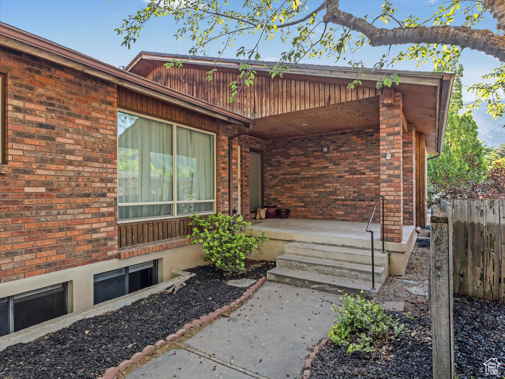 View of exterior entry featuring brick siding and a porch