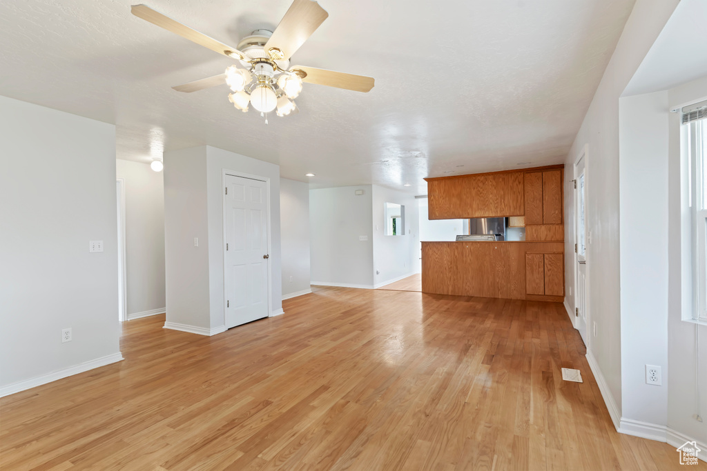 Unfurnished living room featuring ceiling fan and light wood-type flooring