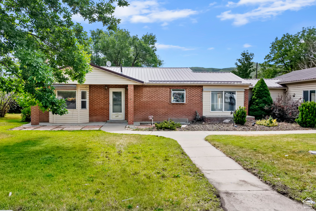 Ranch-style house with brick siding, a front lawn, and a metal roof