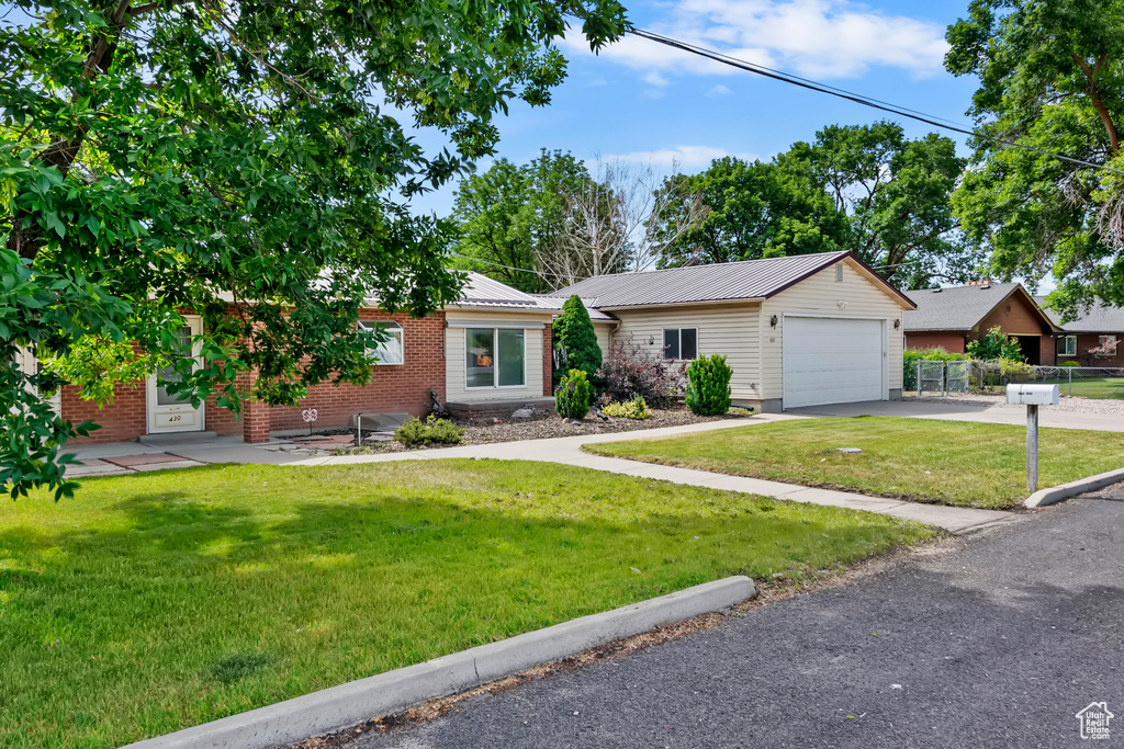 Ranch-style house with asphalt driveway, a metal roof, brick siding, and a garage