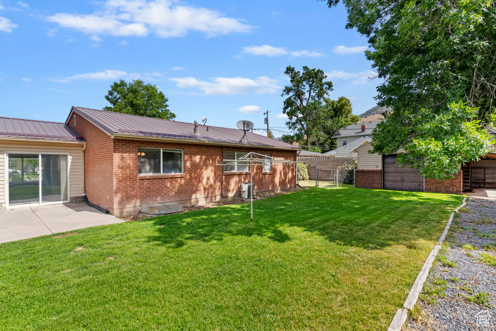 Back of property with brick siding, a metal roof, and a patio area