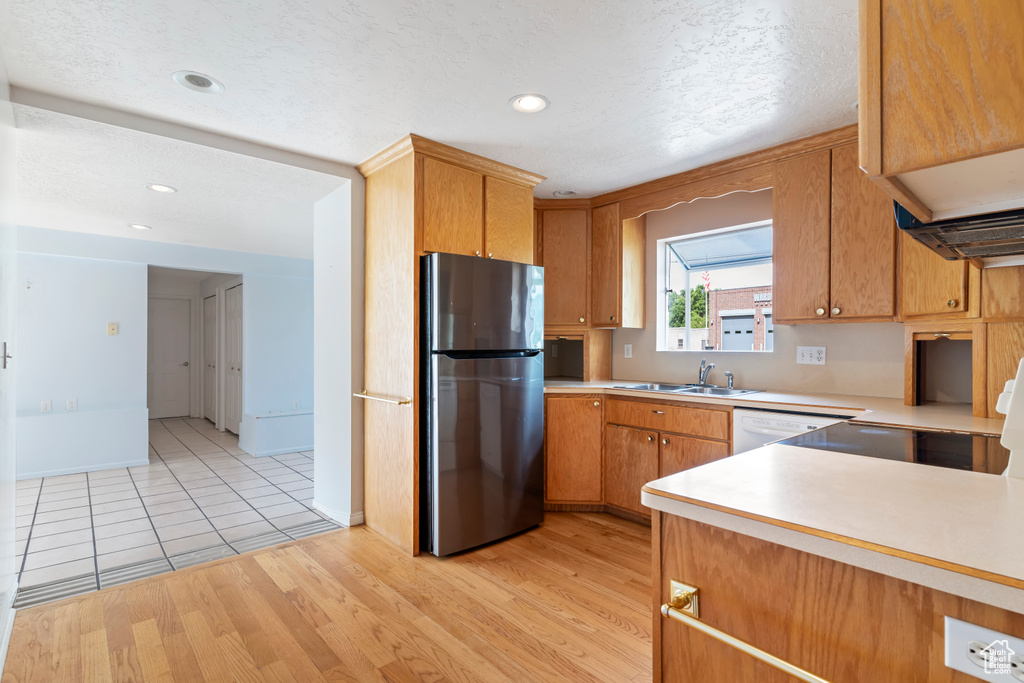 Kitchen with freestanding refrigerator, light countertops, light wood finished floors, recessed lighting, and dishwasher