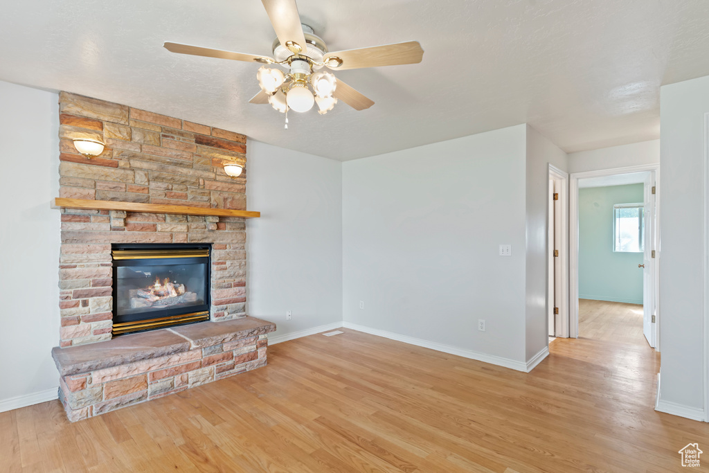 Unfurnished living room featuring ceiling fan, wood finished floors, and a fireplace