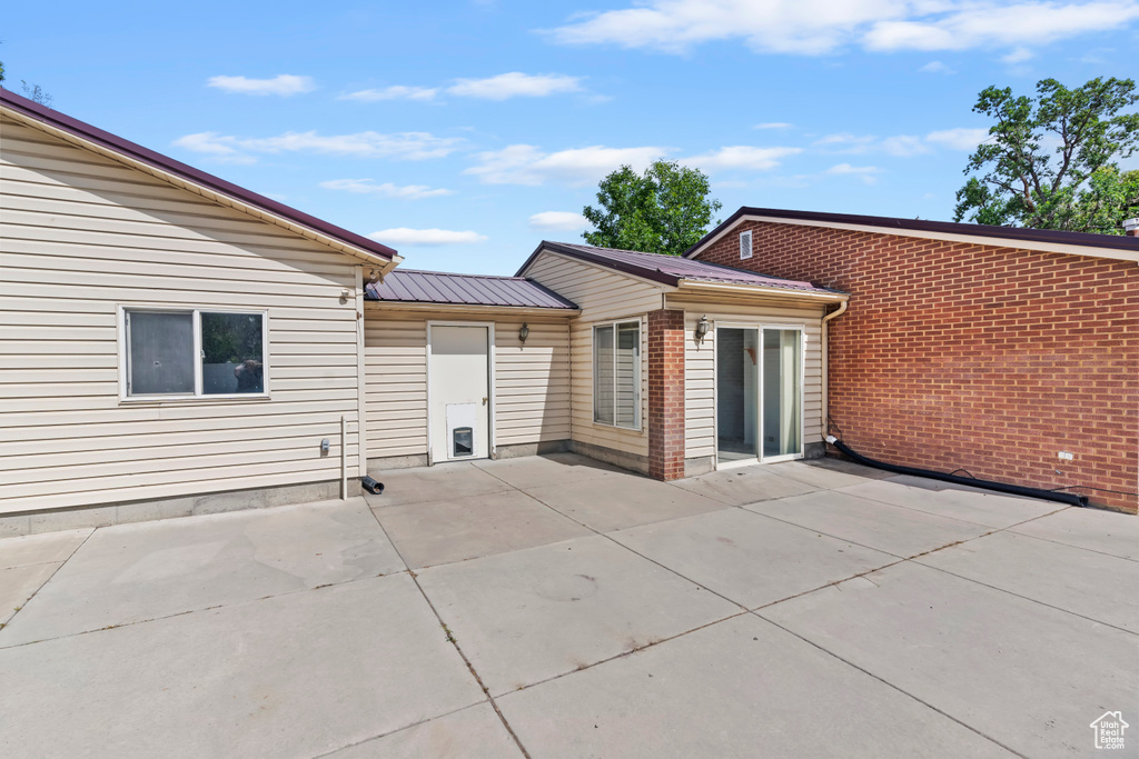 Rear view of house featuring a patio area and a metal roof