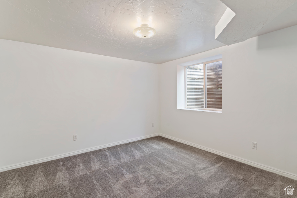 Carpeted spare room with baseboards and a textured ceiling