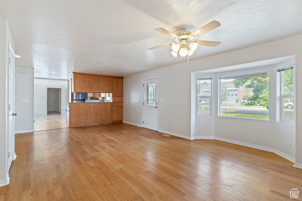 Unfurnished living room featuring a ceiling fan and light wood-style flooring