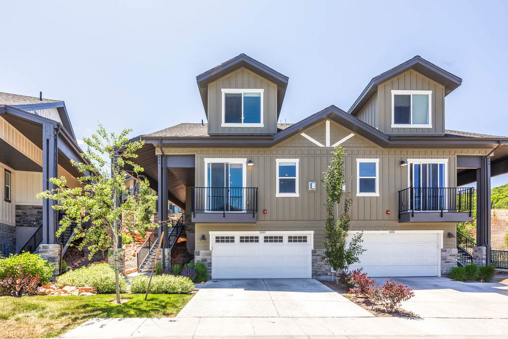 View of front of property with stairs, a garage, concrete driveway, and stone siding