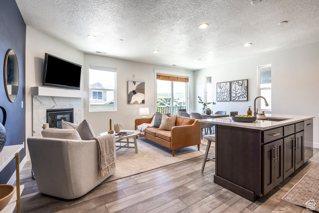 Living area featuring light wood-type flooring, a fireplace, a textured ceiling, and recessed lighting