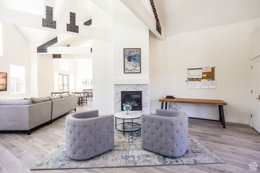 Living area with high vaulted ceiling, wood finished floors, and a premium fireplace