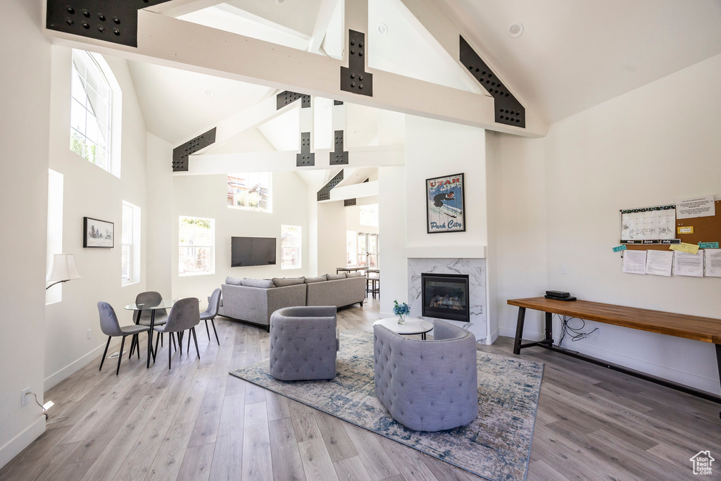 Living area featuring high vaulted ceiling, wood finished floors, beam ceiling, and a premium fireplace