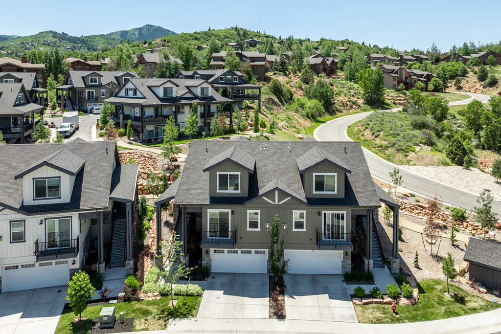 View of front of property featuring a garage, driveway, a residential view, and a shingled roof