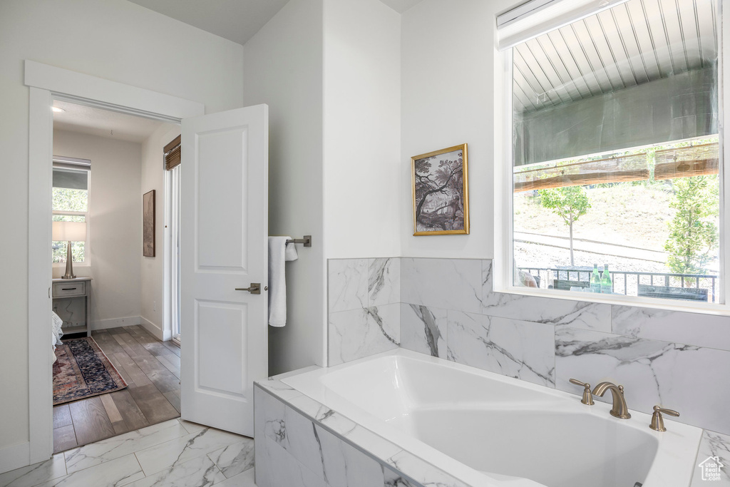 Full bathroom with a garden tub and marble look tile flooring