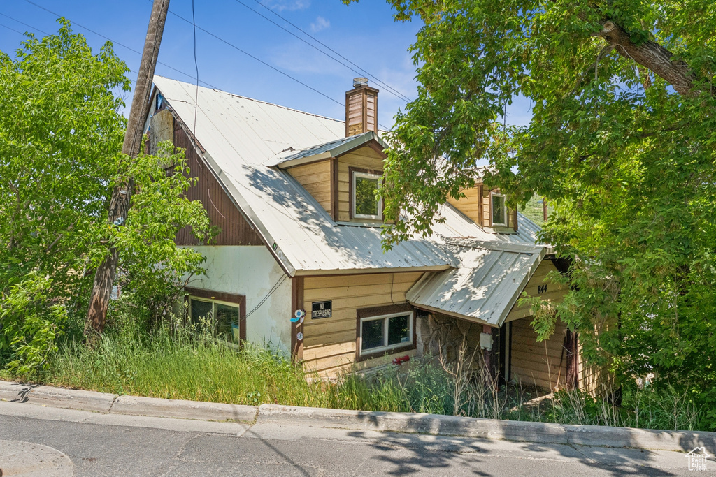 View of front of house with a metal roof and a chimney
