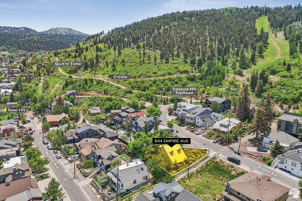 Aerial perspective of suburban area with a mountainous background and a heavily wooded area
