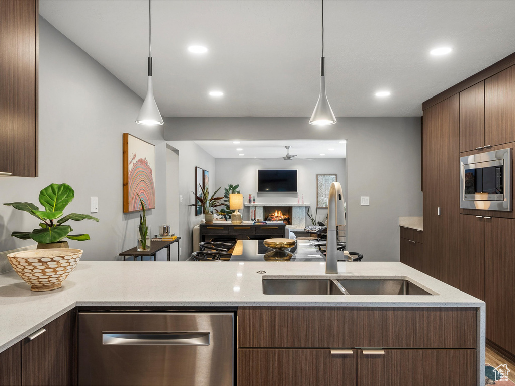 Kitchen with stainless steel appliances, a warm lit fireplace, decorative light fixtures, recessed lighting, and modern cabinets