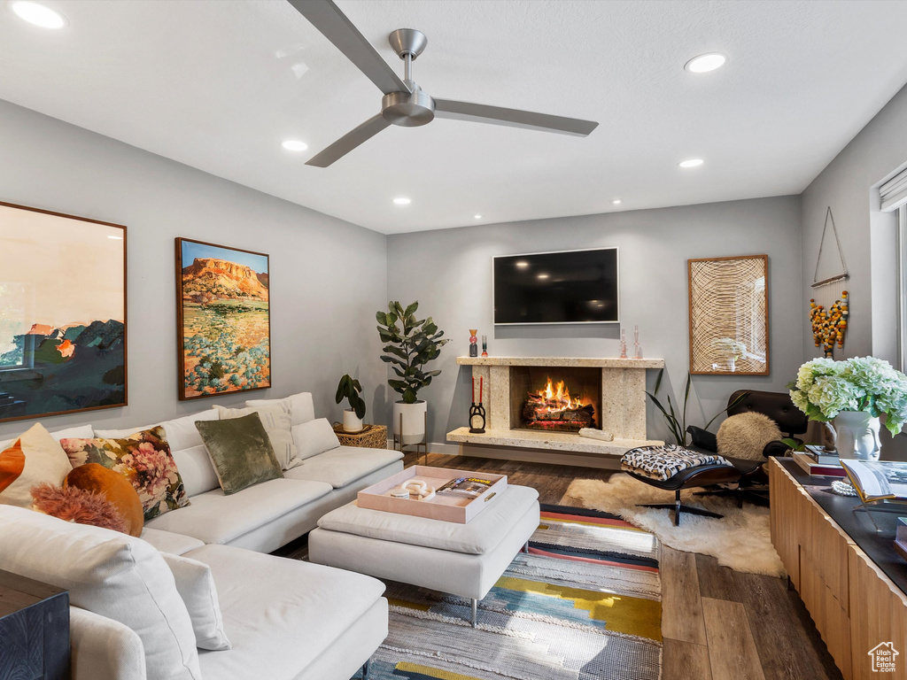 Living room with wood finished floors, a fireplace, ceiling fan, and recessed lighting