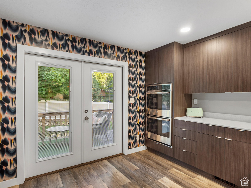 Kitchen with double oven, french doors, light countertops, wood finished floors, and modern cabinets