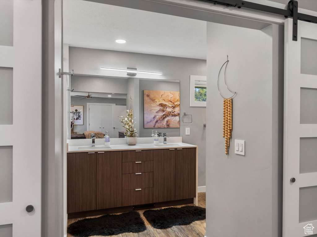 Full bathroom with double vanity, wood finished floors, and recessed lighting