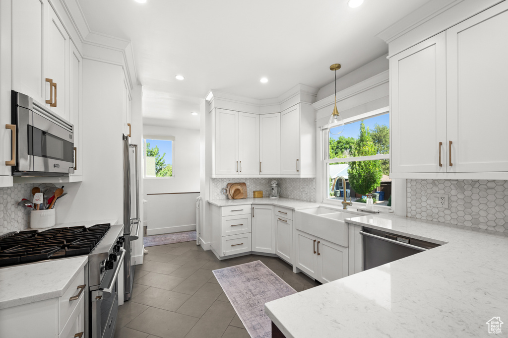 Kitchen with appliances with stainless steel finishes, recessed lighting, white cabinetry, decorative backsplash, and light stone counters