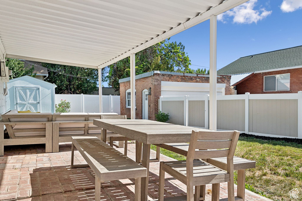 Fenced backyard featuring a shed, outdoor dining space, and a patio