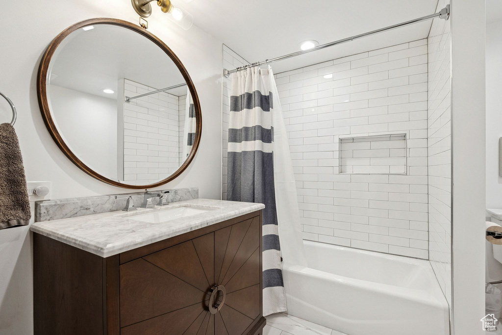 Full bathroom featuring shower / bath combo, vanity, and marble look tiles