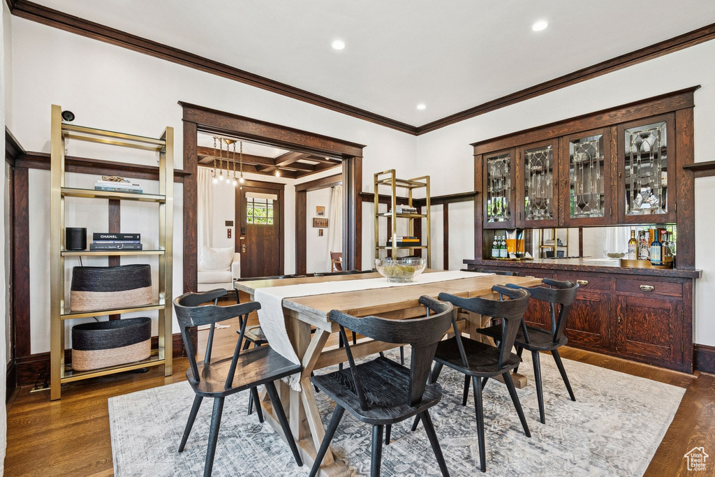 Dining area with crown molding, bar with sink, dark wood-style floors, recessed lighting, and coffered ceiling