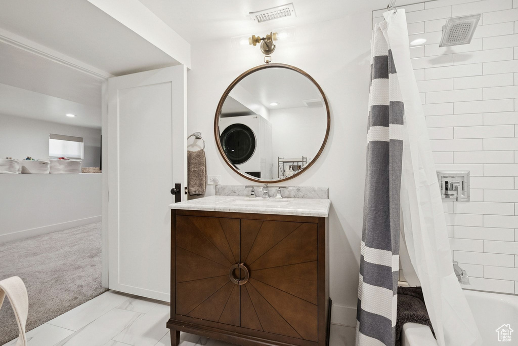 Bathroom featuring vanity and shower / bathtub combination with curtain