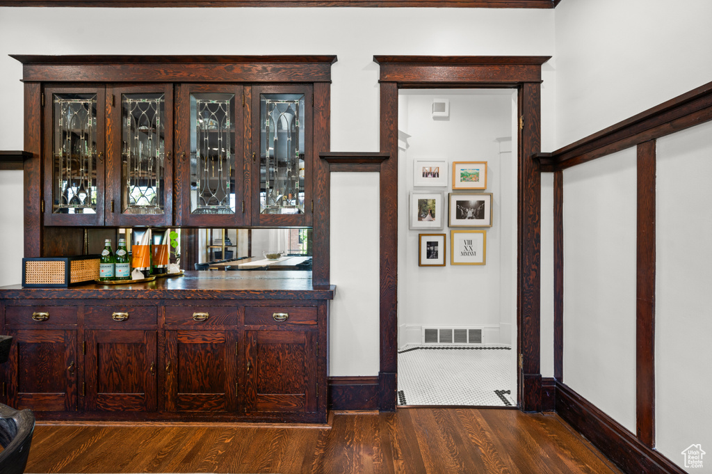 Indoor dry bar featuring dark wood-style flooring and baseboards