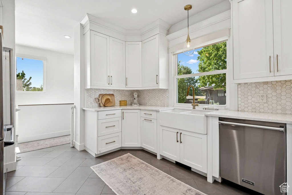Kitchen with stainless steel dishwasher, plenty of natural light, tile patterned flooring, white cabinets, and recessed lighting