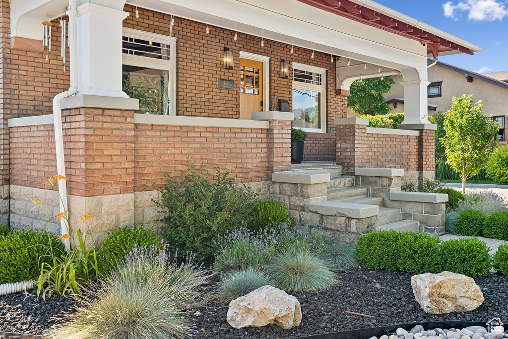 Doorway to property featuring covered porch and brick siding
