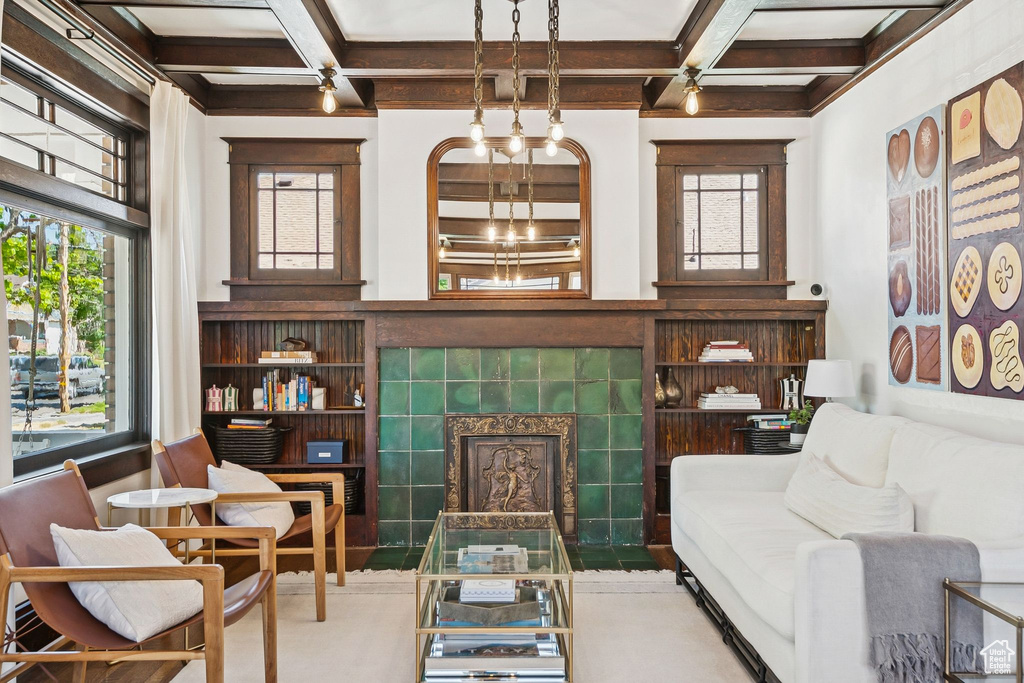 Living area featuring coffered ceiling, beamed ceiling, a tiled fireplace, and built in shelves