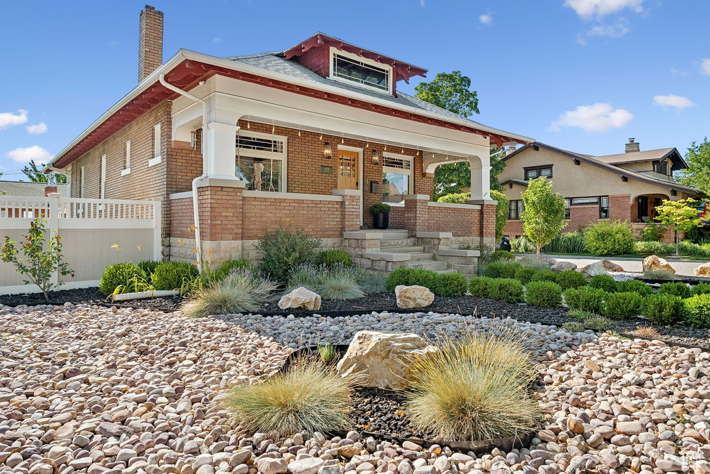 View of front of property with brick siding, a chimney, and a porch