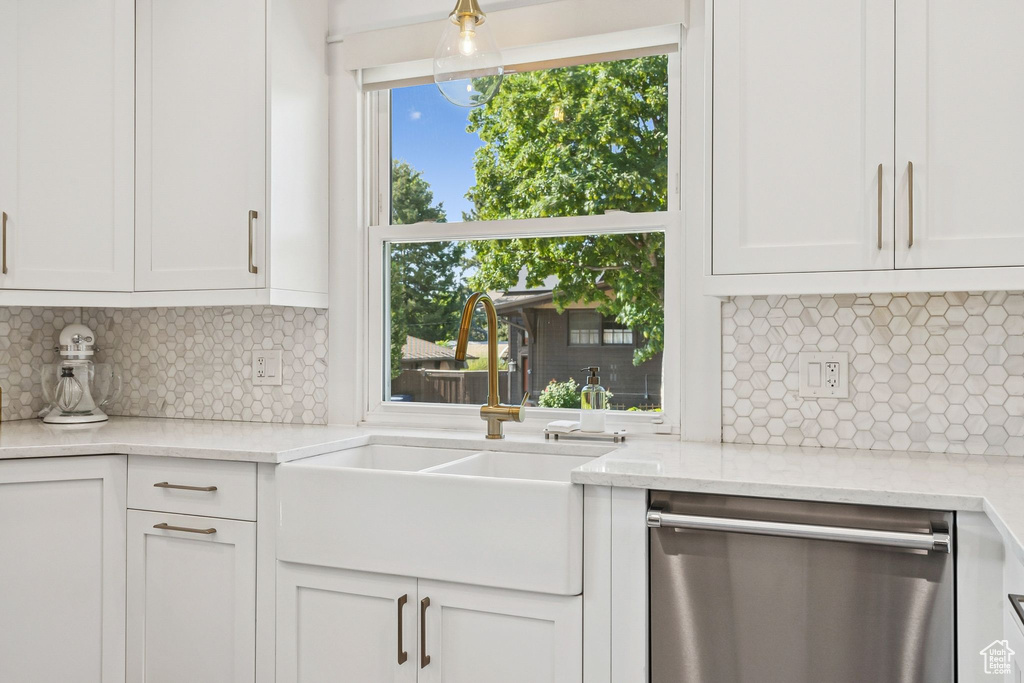 Kitchen featuring dishwasher, white cabinetry, and backsplash