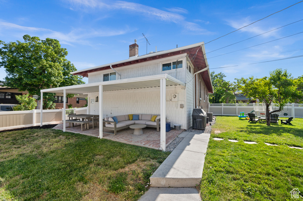 Back of house with a patio area, a chimney, outdoor lounge area, and a fenced backyard