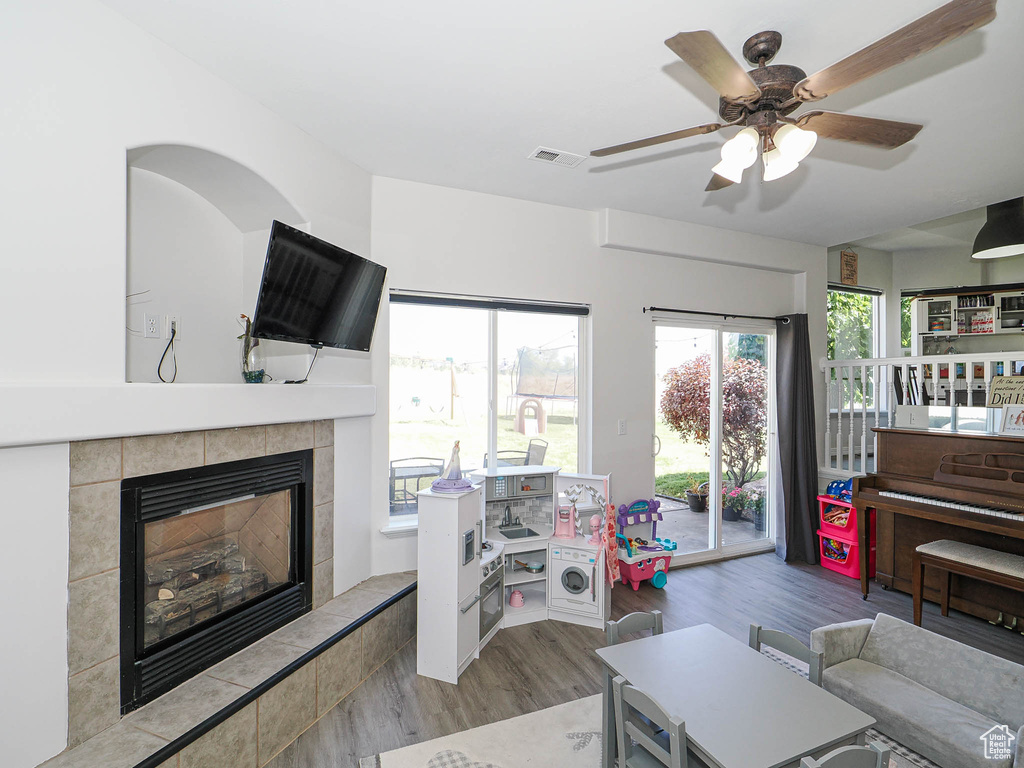 Living room featuring wood finished floors, ceiling fan, and a tiled fireplace