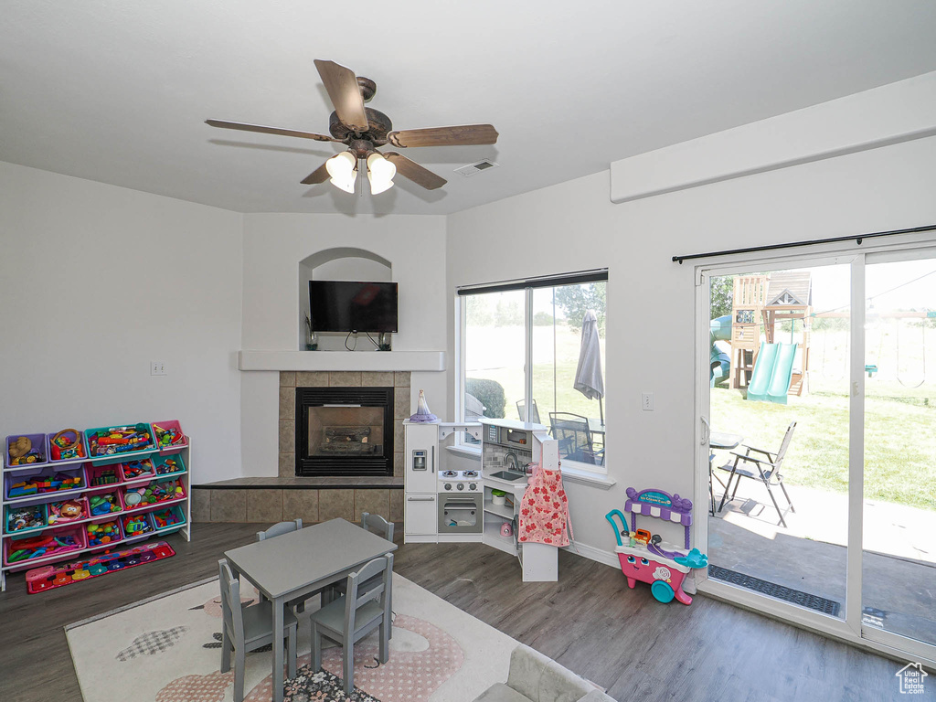 Game room with wood finished floors, a ceiling fan, and a tile fireplace