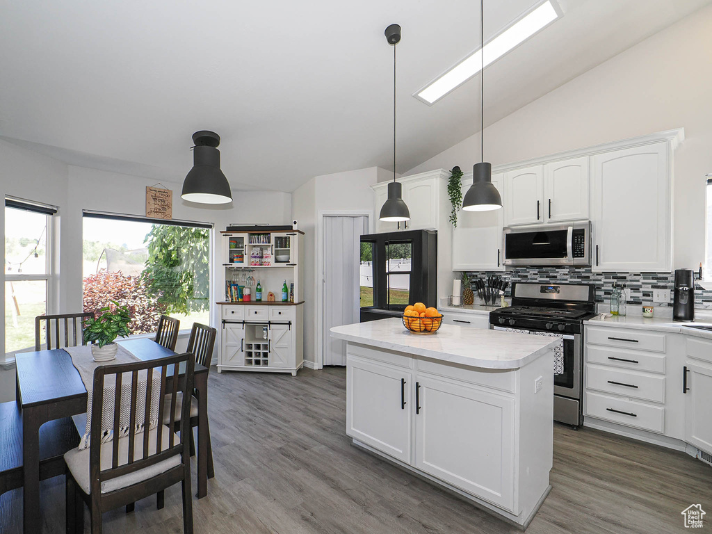 Kitchen featuring stainless steel appliances, tasteful backsplash, light countertops, a kitchen island, and white cabinetry