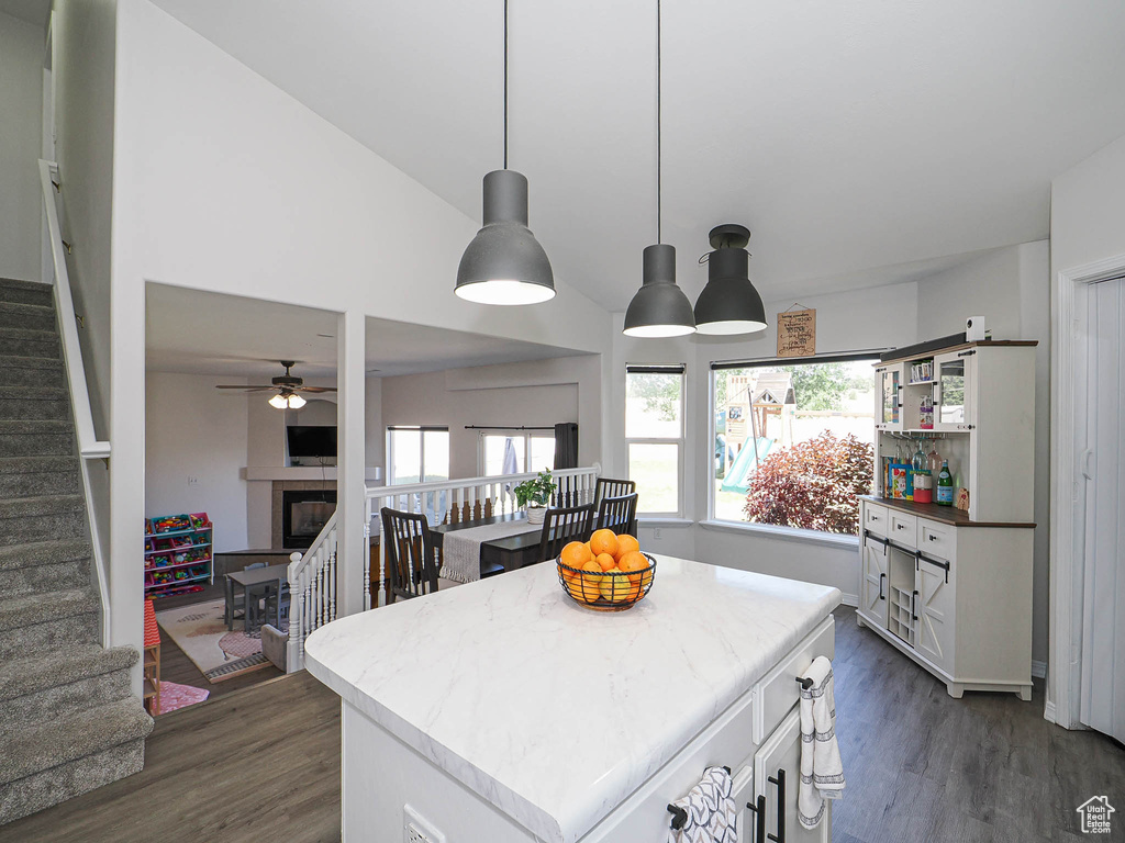 Kitchen featuring dark wood-style flooring, a glass covered fireplace, white cabinets, and pendant lighting