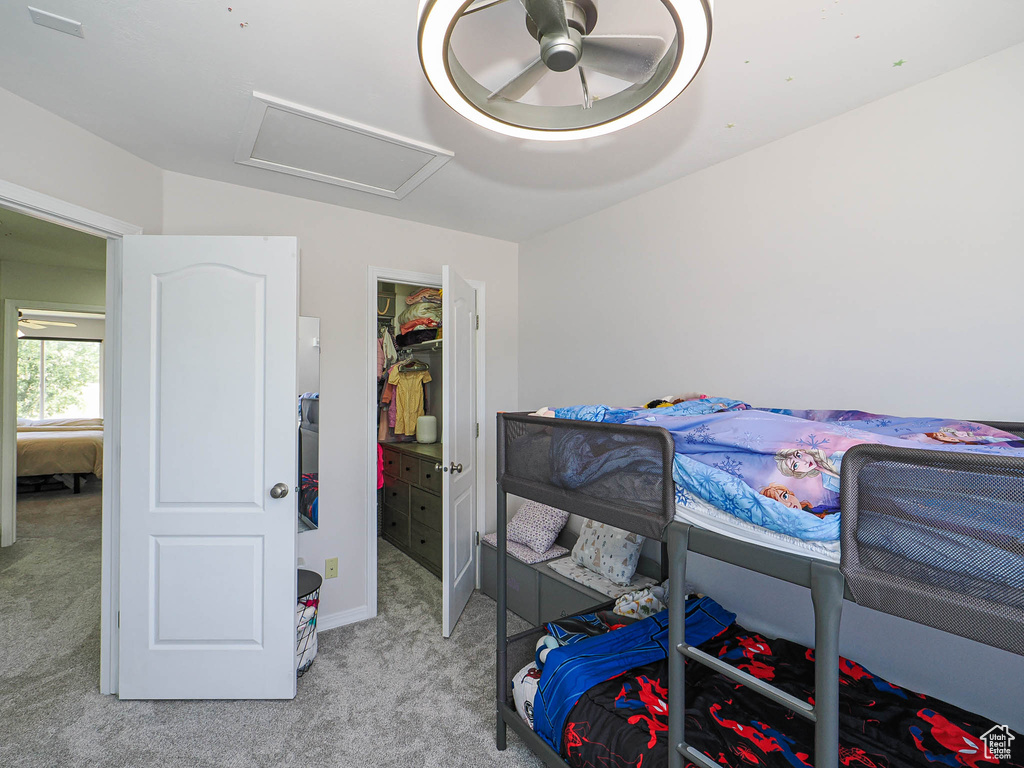 Bedroom with light colored carpet, attic access, a spacious closet, ceiling fan, and a closet