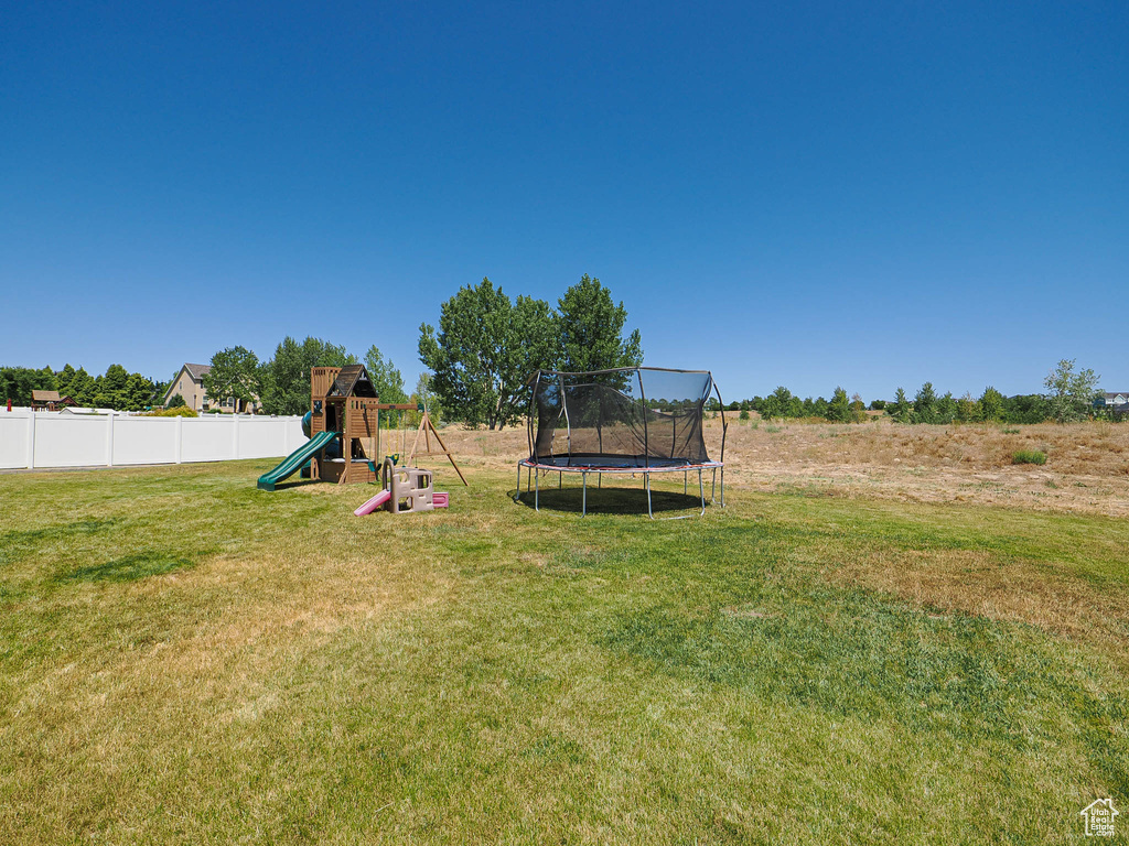 View of yard with a playground and a trampoline